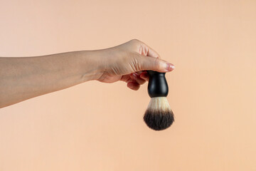 Small black dust brush in hand on a cream background