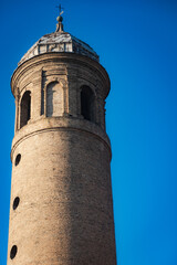 Obraz premium Detail of a historic cylindrical brick bell tower with arched windows and a dome top against a clear blue sky in Ravenna