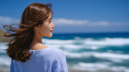 Cinematic back view of young woman standing alone on wide sandy beach, long hair flowing in strong sea breeze, expansive sky and ocean, serene and liberating summer escape