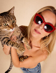 Frau mit roten Sonnenbrillen und einer Katze in der Hand