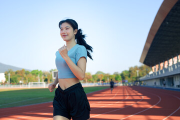 Young Asian woman jogging on outdoor running track in morning sunlight