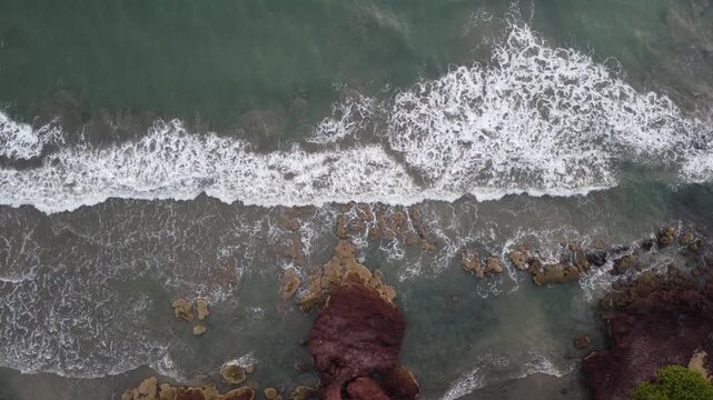 Aerial View of Powerful Ocean Waves Crashing Against Coastal Rocks