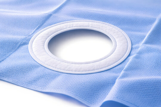 Photorealistic 3D macro product-shot of an unbranded sterile surgical drape folded into a neat square, visible nonwoven fabric microtexture and subtle creases, clean sealed edges