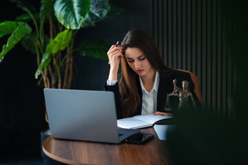 Professional Woman Working on Laptop in Modern Office Environment, working on her laptop in a stylish office with plants in the background.