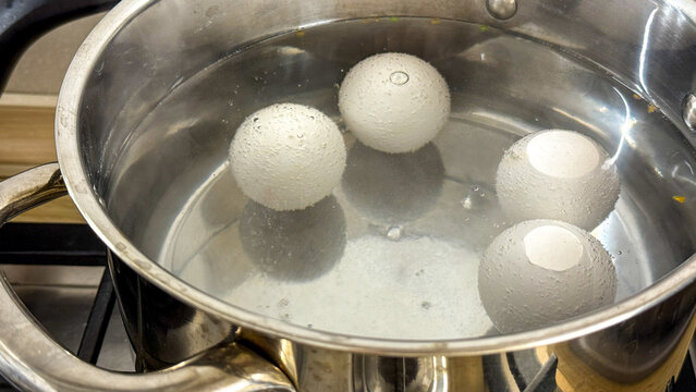 Four alabaster eggs bob amidst steam, a symphony of culinary alchemy, capturing Osterfest and World Boiler Day spirit