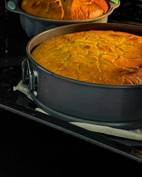 Golden sponge cake basks in oven glow, symbolizing Hygge coziness and World Baking Day, festive warmth in a pan