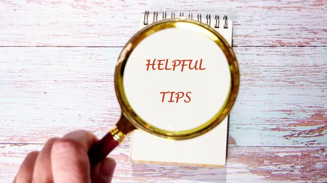A hand holds a magnifying glass over a notebook. The glass reveals the words Helpful Tips written on the page. Its a day filled with learning and sharing