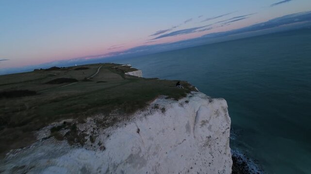 Fpv drone flying along white cliffs of dover coastline at sunset