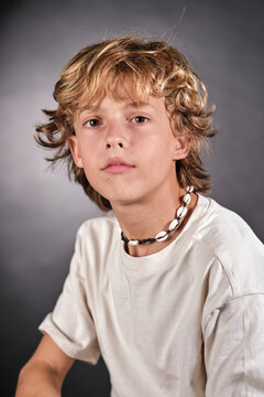 Cute blonde boy wearing shell necklace looking at camera