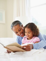 A grandmother joyfully reading a book to her granddaughter while sitting on a bed. Family bonding and storytelling moments.