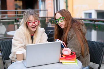 Friends work together on school project outside during sunny day with laptop and books