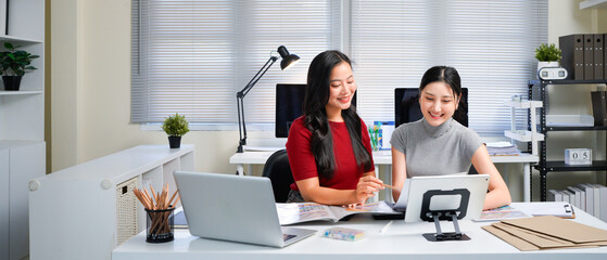 Colleagues in office. Two Businesswoman discussing work in office. Two friends in working together, Creative Director and Project Manager Compare Business Results on Laptop and document in an Office