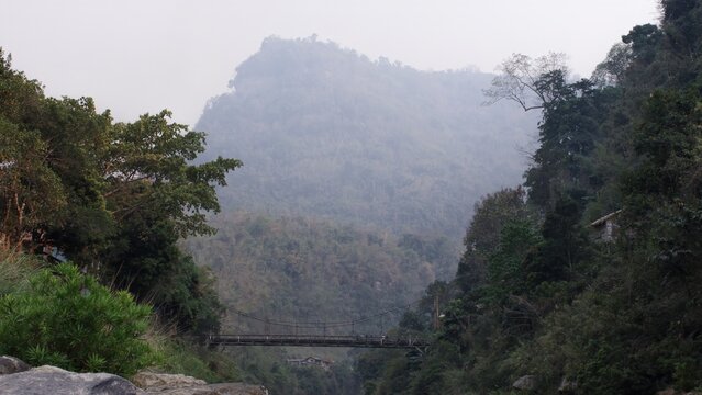 steep mountain landscape with fog and a old bailey bridge over a river