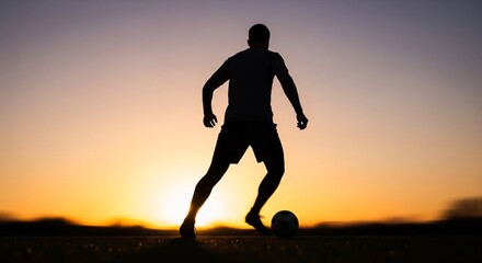 Soccer player silhouette dribbling ball against dramatic sunset sky.