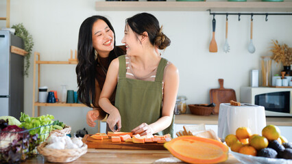 Lesbian couple cooking together in a kitchen, one woman lovingly embraces her partner from behind, concept of a happy domestic partnership, love, and lgbtq family lifestyle