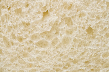 Close-up of cut soft sourdough loaf inside. Abstract airy yeast sponge texture with holes. Healthy rustic nutrition concept and bakery shop backdrop. Photo