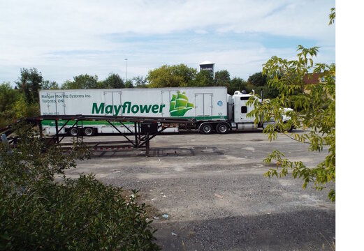 Gloucester, ON, Canada-July 6,2025: A white "Mayflower moving truck" parked in a gravel lot on Cyrville Road.