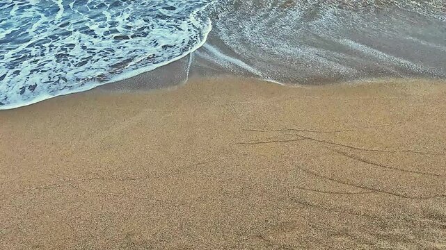 Gentle ocean waves washing over sandy Mediterranean beach shore