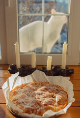 A freshly baked pie is on the windowsill, and a white cat is looking in the window.