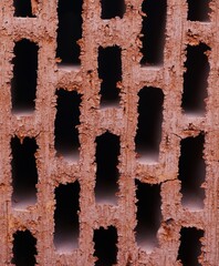 Wnętrze cegły z widocznymi prześwitami i porowatą strukturą. Detale pokazują fakturę materiału budowlanego. © Adam