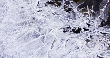 Zamarznięty lód ukazuje swoją strukturę z bliska, z wyraźnymi kryształami i fakturą powierzchni. Naturalny, zimowy detal przyrody. © Adam