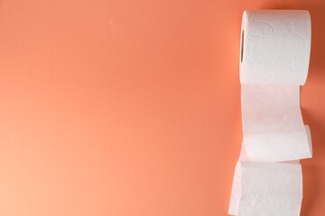 Obraz premium Toilet paper roll on coral background, top view. Space for text