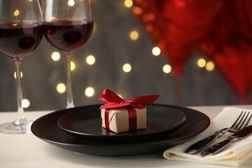 Beautiful place setting with gift on table, closeup
