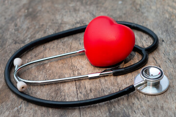Stethoscope and red heart line resting on an old wooden floor, rustic medical concept.