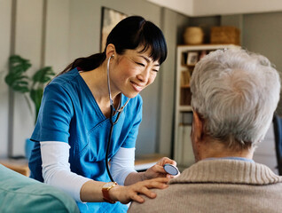 Doctor or nurse caregiver with senior man at home or nursing home using a stethoscope during an exam