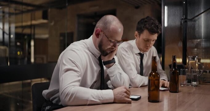 In a stylish urban cafe, two men in white shirts connect through their devices, enjoying a brief pause from work