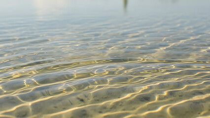 Serene water surface with golden light reflections rippling