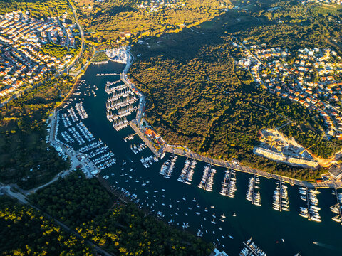 Cinematic aerial view of a luxury sailing marina with hundreds of yachts at sunset. Top-down perspective of a prestigious nautical harbor and safe haven. Marina Veruda, Pula, Croatia.