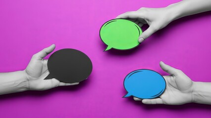 Obraz premium Hands holding colorful speech bubbles on vibrant pink background 