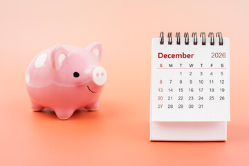 Desk calendar for December 2026 and pink piggy bank.