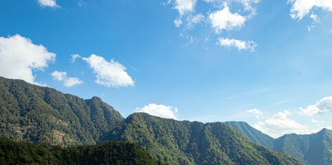 Scenic Mountain Landscape Under Bright Blue Sky with White Clouds
