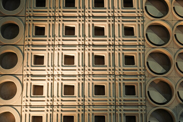 Brick with a repeating geometric pattern on home partition wall. The bricks are a warm brown color and the image is taken from a low angle, creating a sense of depth, Close up.