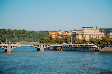 Obraz premium Beautiful Prague River Scene Captured, Serene Prague River With Historic Bridge And Skyline
