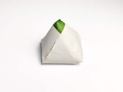 Close up of authentic nasi lemak bungkus wrapped in paper and green banana leaf isolated on white