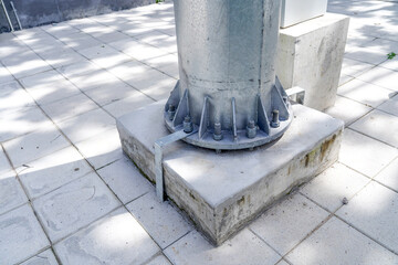 Ground wire connected to outer metal plate of a power pole base for electric safety. View from the walkway.