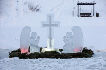 Baptismal font for epiphany bathing on winter lake. Ice cross and figures of angels