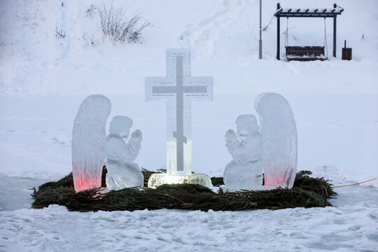 Baptismal font for epiphany bathing on winter lake. Ice cross and figures of angels