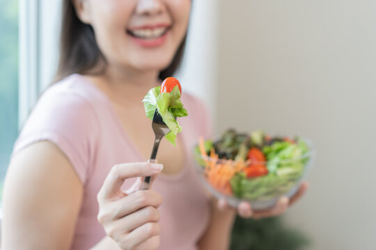 Diet concept, happy smile asian young woman use fork to prick tomato, fresh vegetable or green salad, eat nutrition food isolated on background, low fat to good body, getting weight loss for healthy.