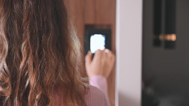 woman hand presses modern digital dial thermostat display to increase heating system operating temperature smart home. Air conditioner home control panel on wall lowers order to save on utility bills.