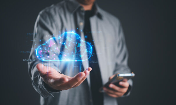 Businessman holding smartphone with virtual cloud computing hologram. Global network connection, data storage security, and digital transformation concept on dark background. - Powered by Adobe