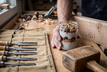 A craftsman holds a healthy chia pudding breakfast in his woodworking shop.