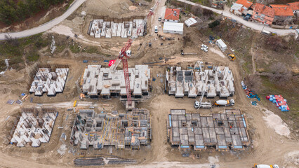 Obraz premium Bird's-eye view of a multi-block residential project under construction with heavy machinery and foundation work in progress.