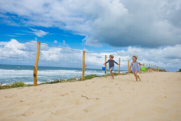 Happy boy with girl joyfully run to sandy beach near ocean waves