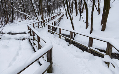 A snow covered wooden bridge with a path leading to it