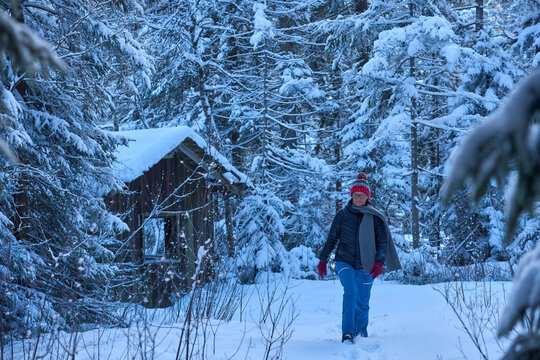 Active senior woman hiking in snowy winter landscape at sunset in the Bregenzerwald, Vorarlberg, Austria