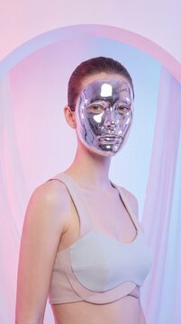 Silver face mask pink gloves futuristic fashion woman metallic beauty modern style skincare reflective minimalism elegance pastel background confidence